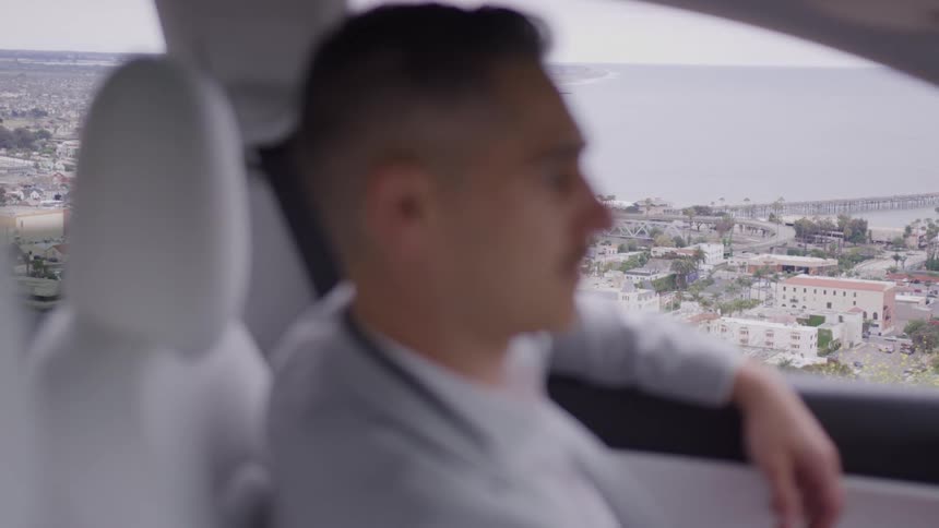 Close up of a young man sitting contemplatively in a vehicle during daytime