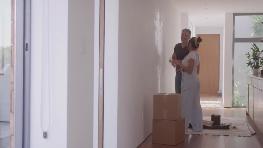 A man and a woman painting a wall and having fun