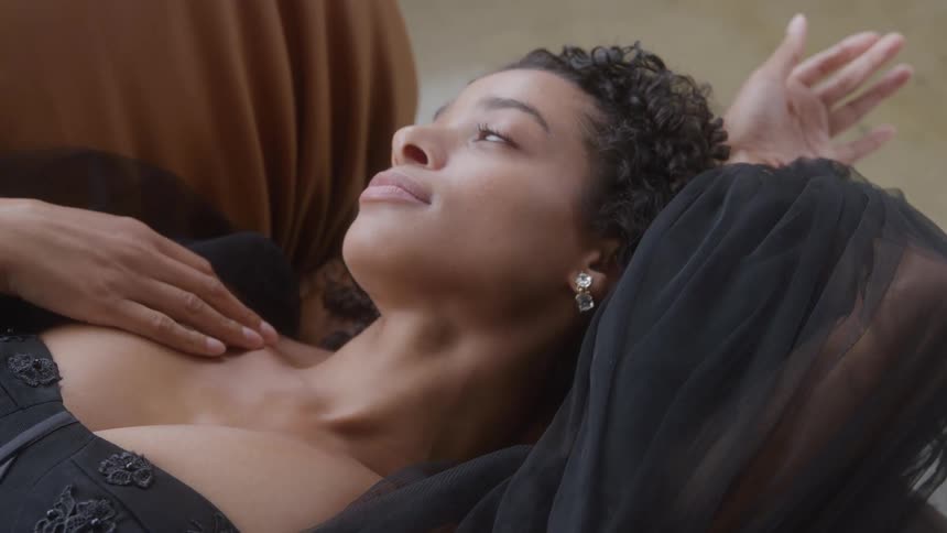 Woman lying down in elegant outfit gazing upward softly