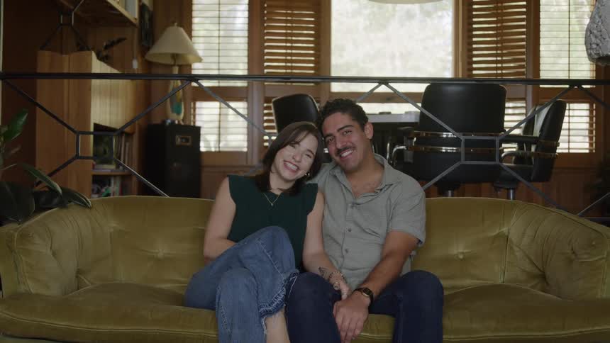 A happy couple sitting on the couch looking at each other romantically