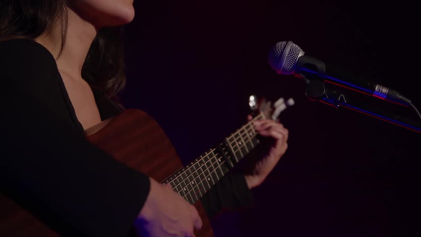 Female musician plays the guitar as she performs