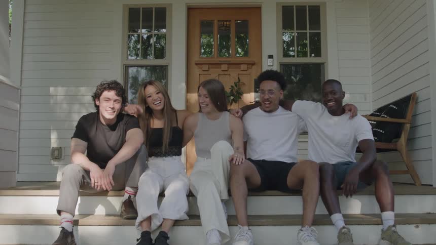 Group of friends smiling together on a house porch