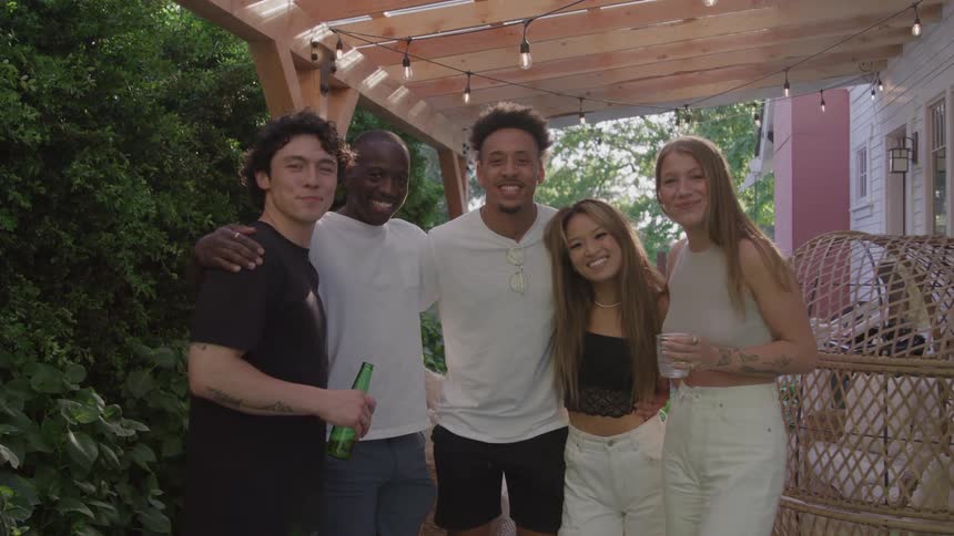 Friends smile together in a patio lit by hanging lights