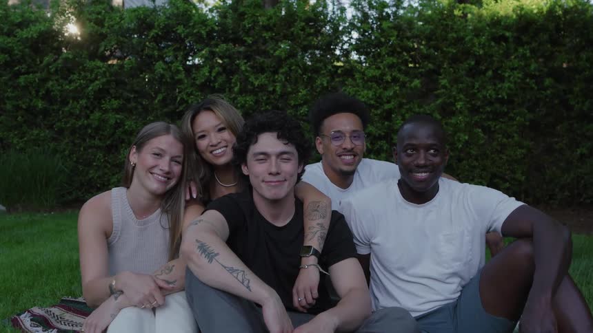 Group of friends sitting together smile at the camera in a garden
