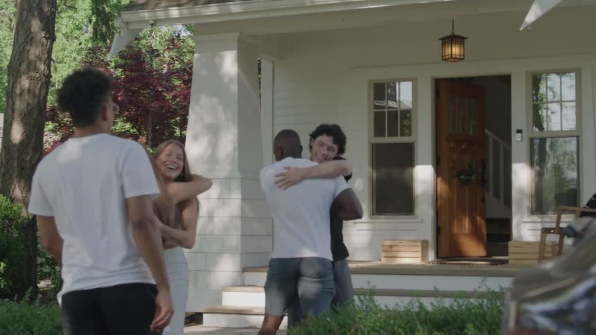 Friends hug and greet each other in front of the house during the day