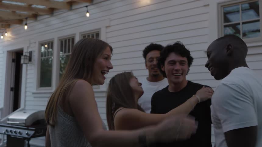 Friends chat and laugh together on the patio at dusk
