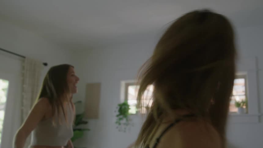 Two friends with suitcases arrive at the room and happily throw themselves onto the bed