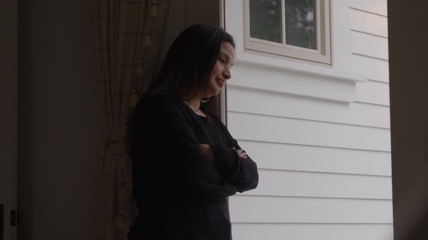 Woman with crossed arms looking out the doorway