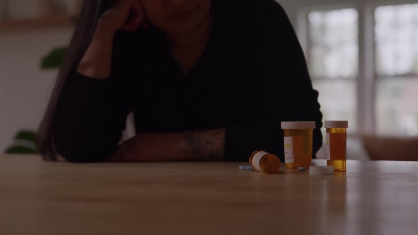 Woman looks at medicine bottles on the table in a quiet room