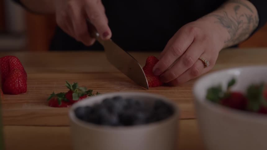 Woman standing at the kitchen counter slicing strawberries