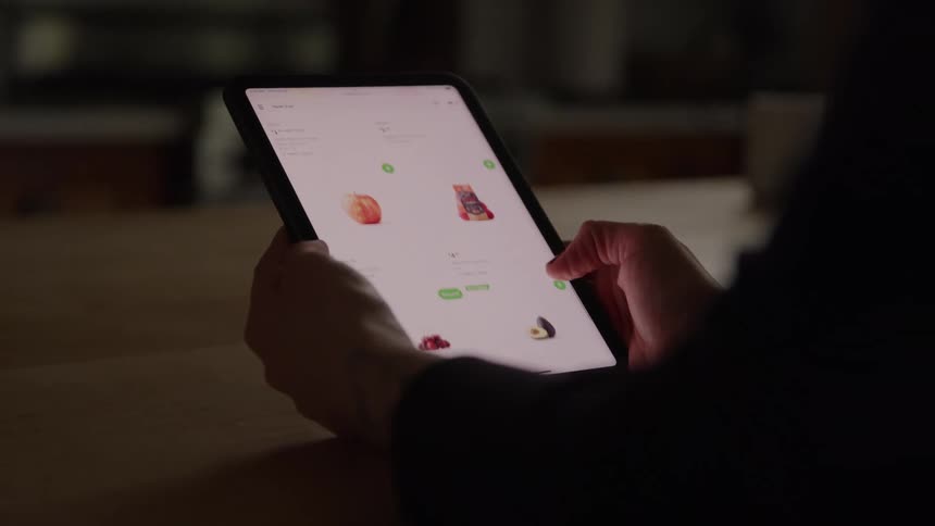 A persons hand holding a tablet with a bright white screen where they are running their finger across the screen