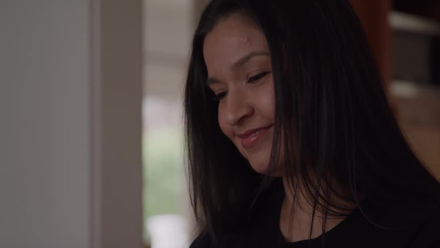 Woman smiles softly while looking at something in front of her