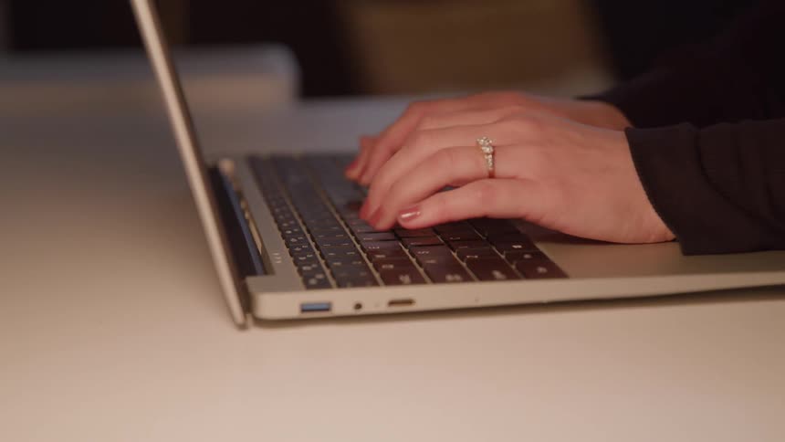 Womans hands typing on the keyboard of a laptop computer