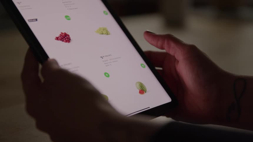 Person holds a tablet browsing fruits on an app