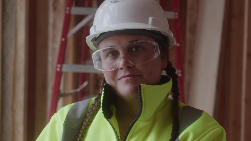 Woman in reflective uniform and hard hat observes the construction site