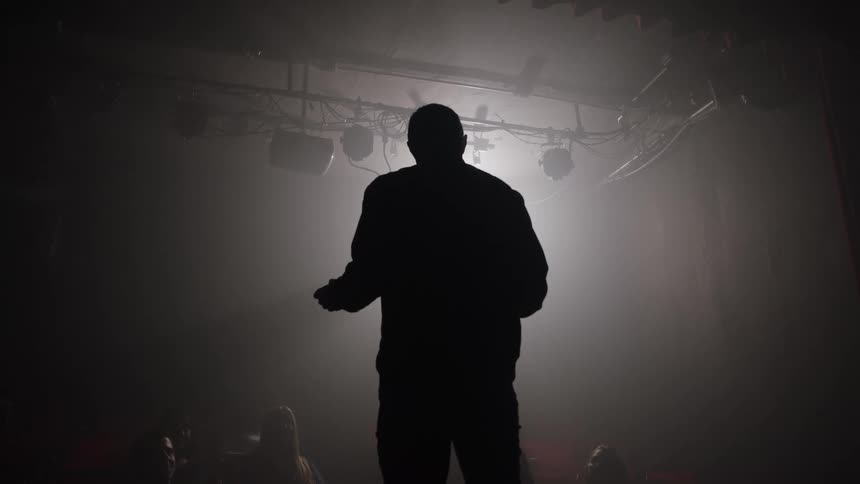 Man performing on stage under strong backlighting
