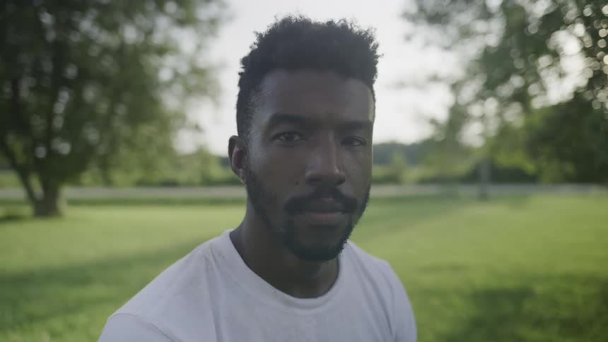 Man standing in a field near the road turns his head to stare