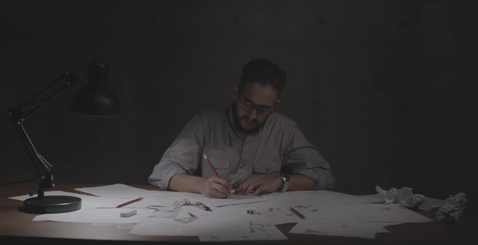 A man sits in a dark office writing