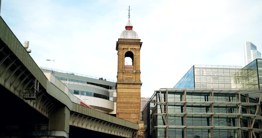 Bell tower stands taller than the nearby buildings and the raised highway on a cloudy day