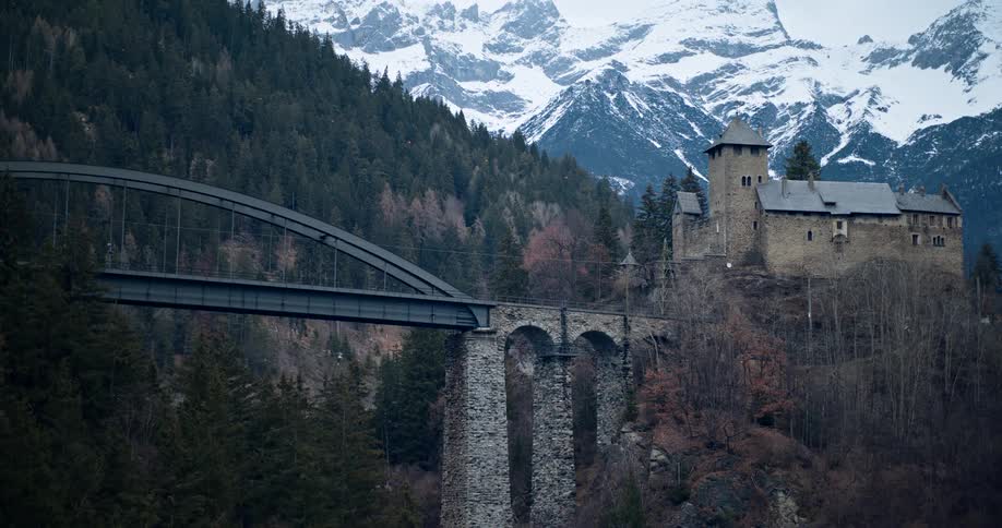 An rocky arch bridge in front of a huge snowy mountain range
