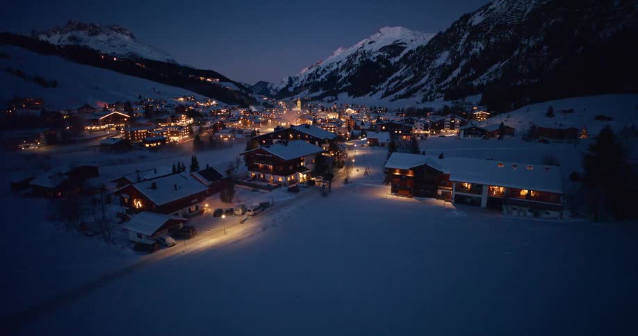 Aerial of houses in a mountain light up village on a winter night