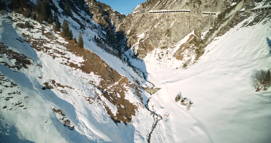 Aerial of a snow covered valley with a stream winding between rocky mountains
