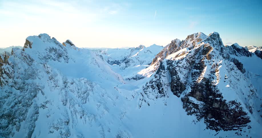 Aerail shot of a craggy mountain range covered in snow on a bright winter day