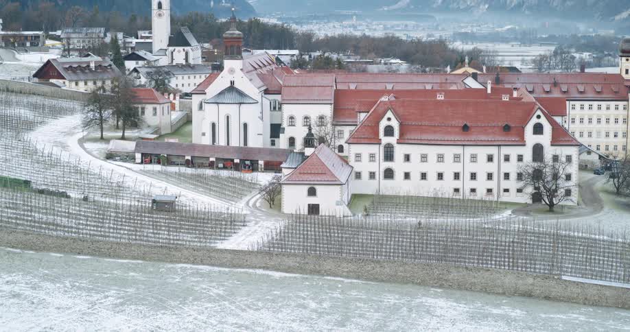 A rural mountain town with monastery with a dusting of snow in front of a mountain range