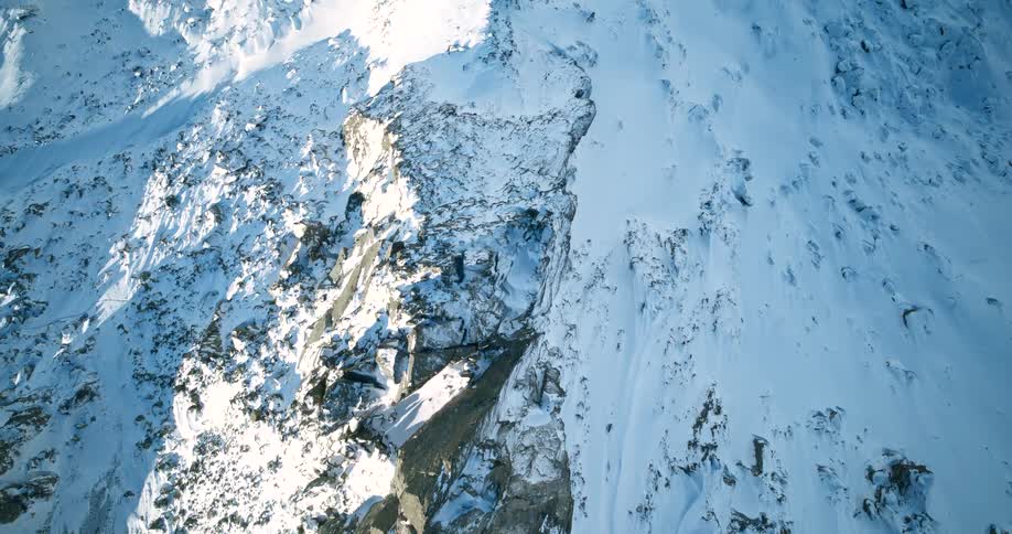 Top shot of a mountain peak of a large snowcovered rocky mountain on a clear sunny day