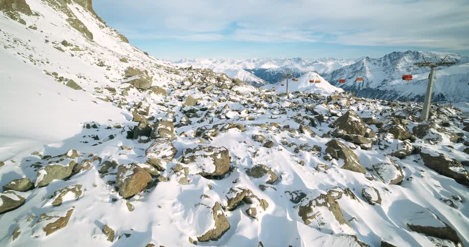 Ski lift benches move on cables over the rough terrain of rocks on mountains