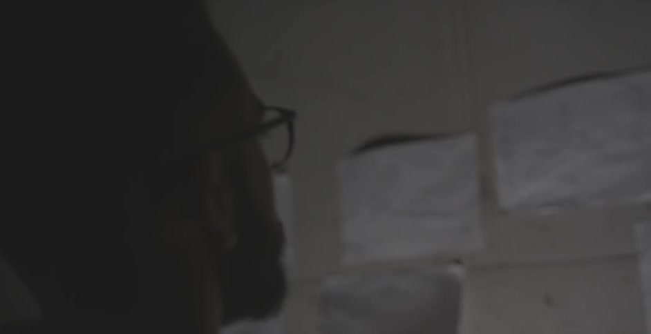 A man looks at the notes taped to a wall