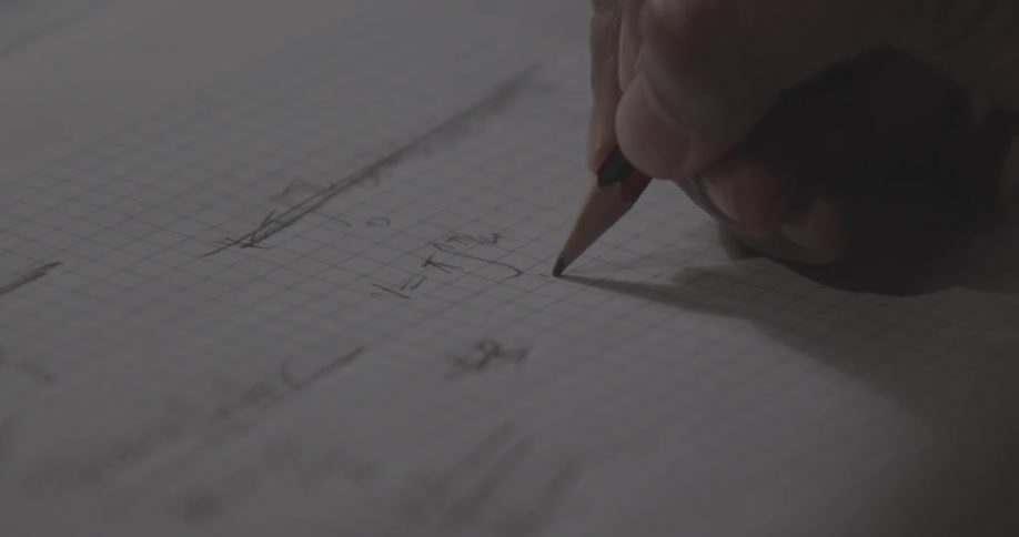 A person drawing and writing on some graph paper at a close up view