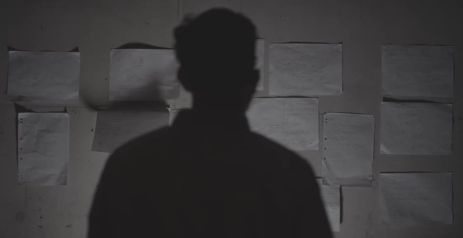 Man standing and looking at a bunch of papers on a wall