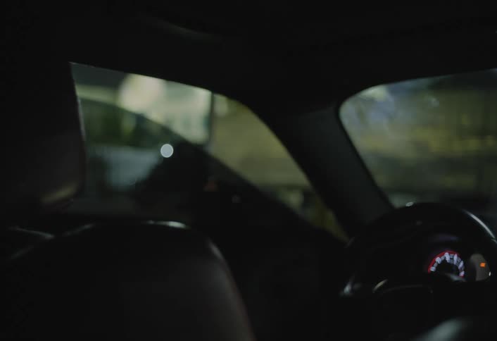 Woman in a dark dress leans over and gets out of the car at night