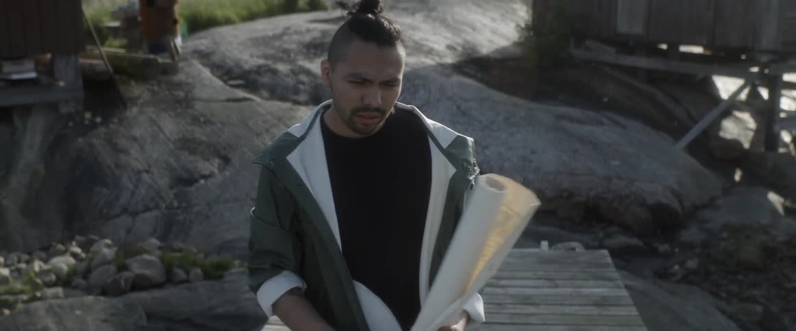 A man is walking over rocks by a shed