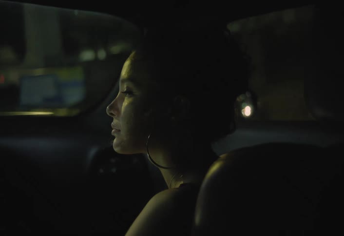 Woman sitting in a car passing through the city at night looks around