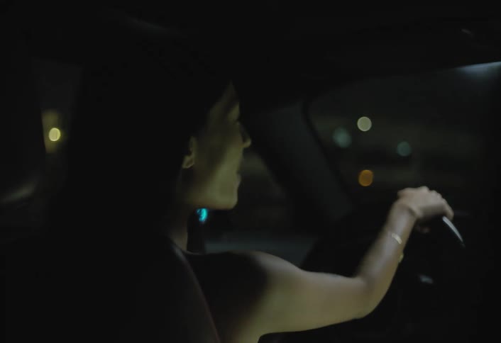 Woman drives at night with a relaxed expression