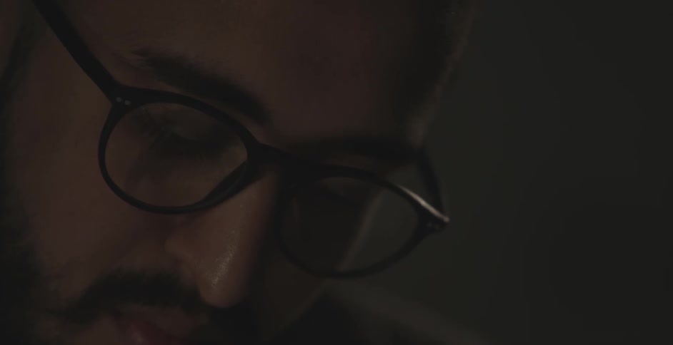A close up view of a man with glasses looking down at something and working