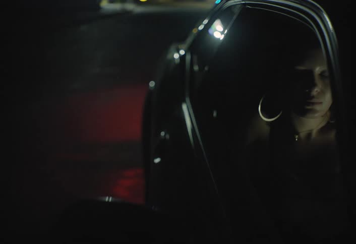 Woman looks out the car window illuminated by red lights