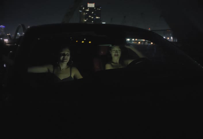 Two young women traveling in a car on a road outside of the city