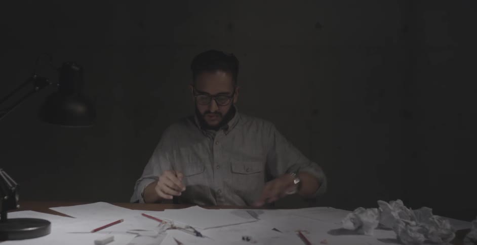 Man crumbles up a paper ball working at a desk