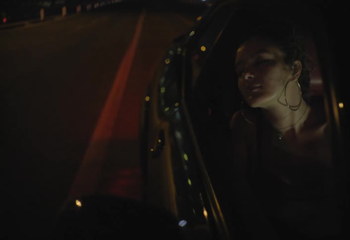 Woman gazes at the road through the car window lit by night lights