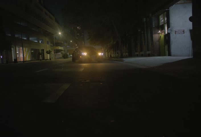 Car traveling on the road crosses over and parks as headlights glow in the darkness