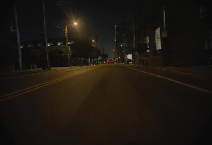 Tail lights glow in the darkness as a car takes off down the road