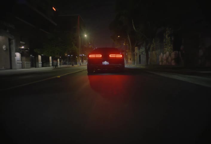 Sports car drives down an empty street lit by lampposts at night