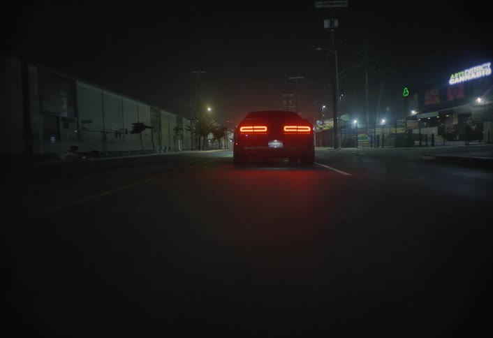 Tail lights glow in the darkness as a car travels on the road
