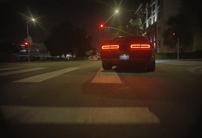 Sports car speeds down an empty avenue under urban night lights