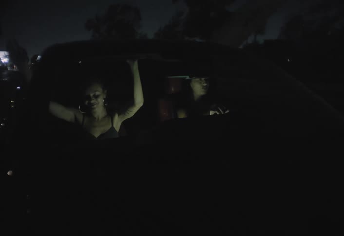 Two women are singing and dancing in their seats as they drive in a car