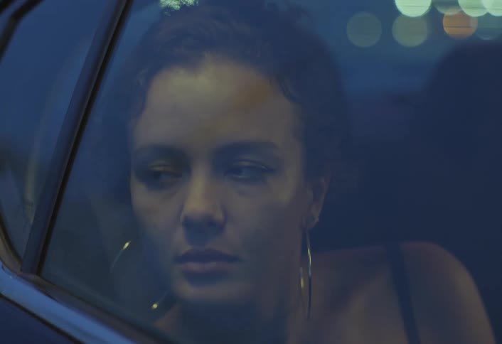 The face of a woman inside a car looking out a closed window