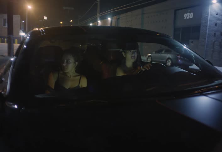 Two young women in a parked car move on the road in light traffic